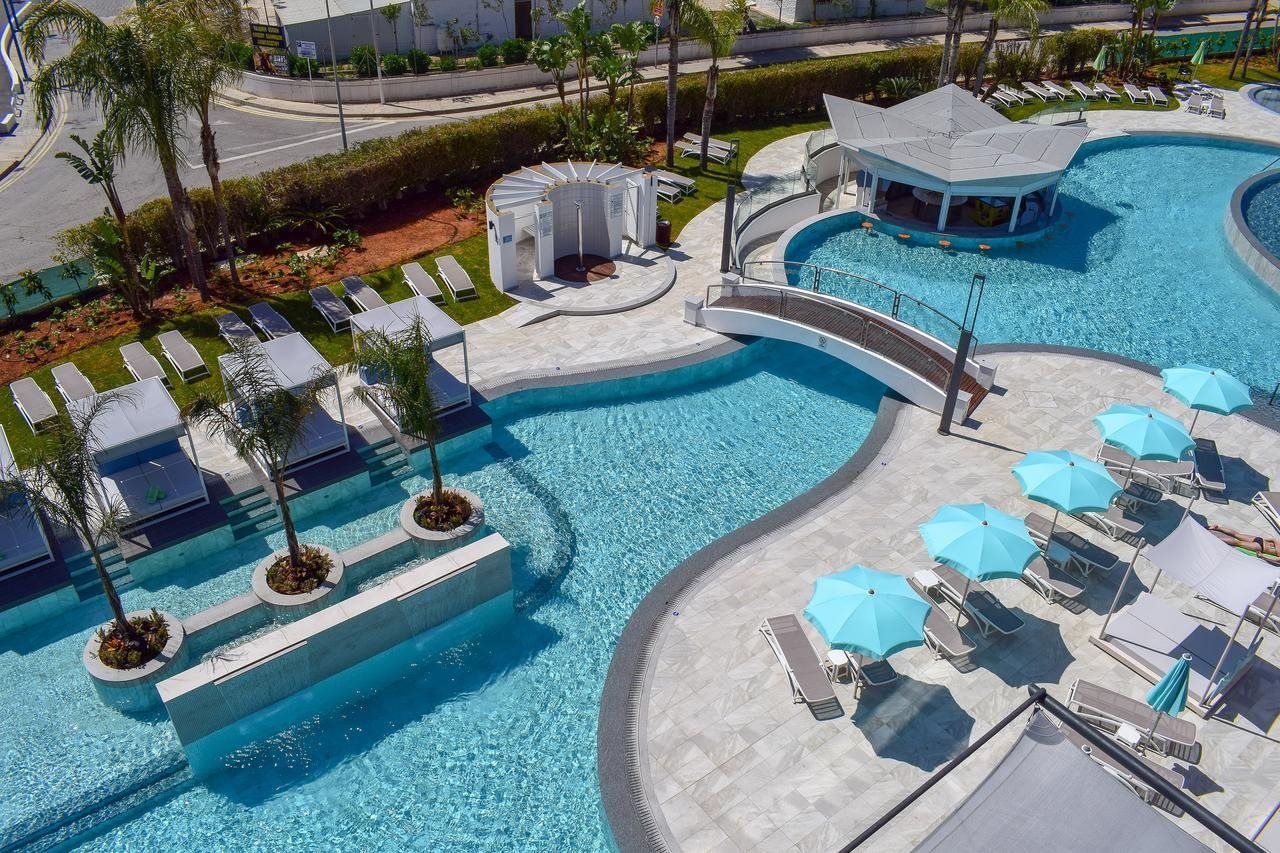 Faros Hotel i Ayia Napa har en stor fri form pool omgivet af et poolområde med palmer og liggestole.