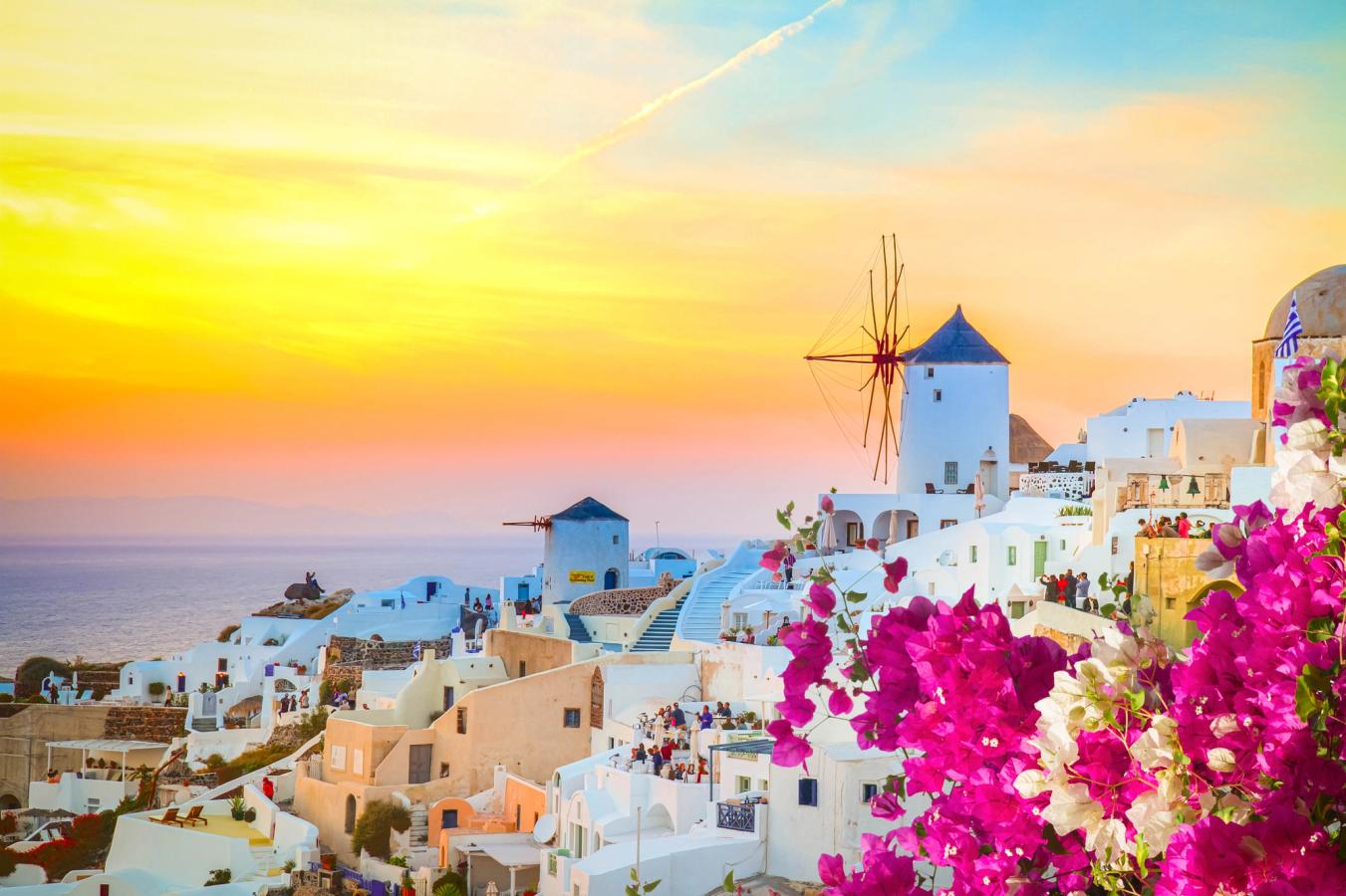 Utrolig flott solnedgang over de hvite husene og rosa blomster i Oia på Santorini