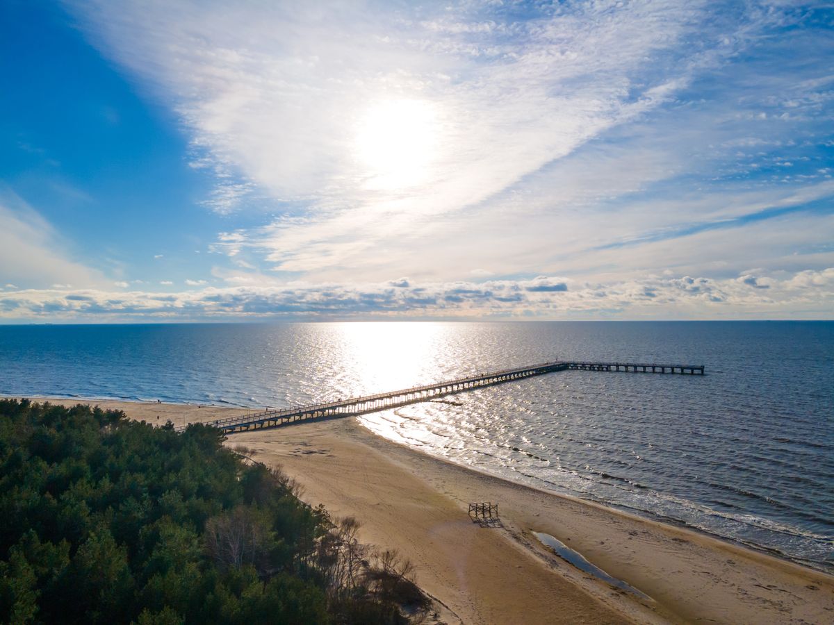Bildet viser sandstranden i Palanga med den lange piren i bakgrunnen. 