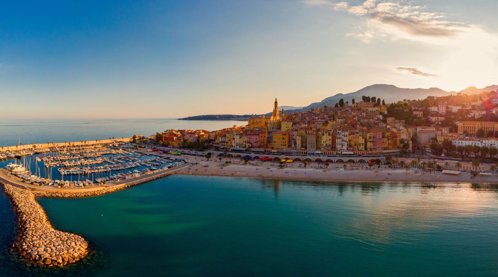 Bildet viser havneområdet inn mot byen Menton. I midten kan man se bykjernen med sine pastellfargede bygninger i oransje, gult og rosa