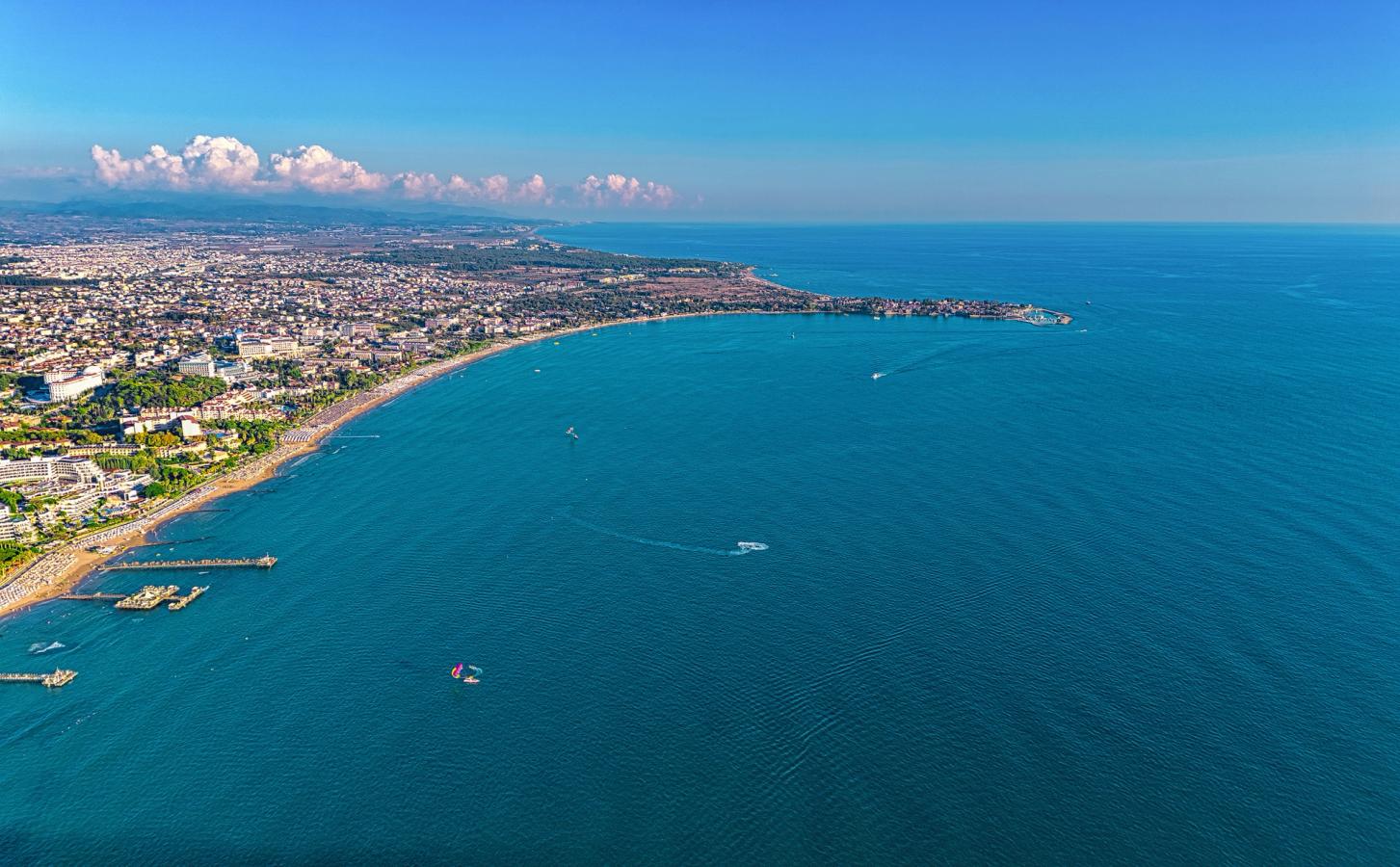 Billedet viser et overblik over byen Side og de lange strande langs kysten. Det stille, blå hav har en smule småbådtrafik. Himlen er næsten skyfri.
