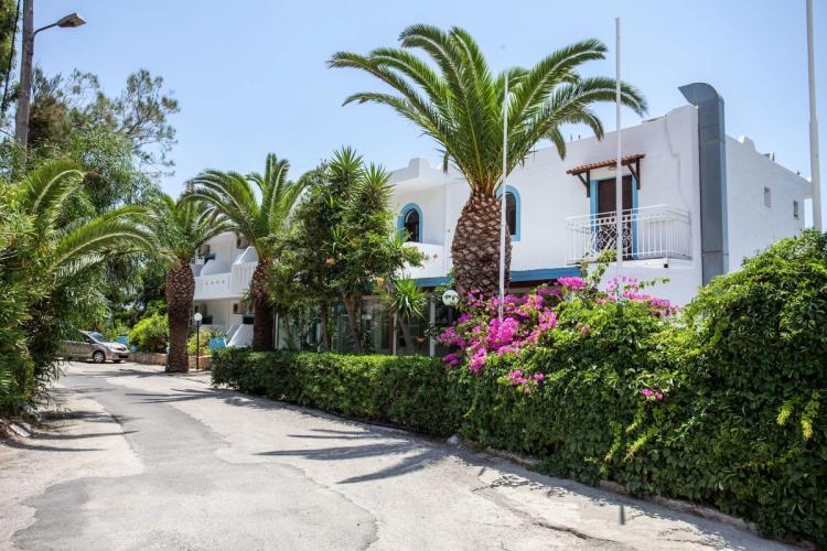 Palmer og rosa blomster ved inngangspartiet til hotell Myrtis i Plakias 