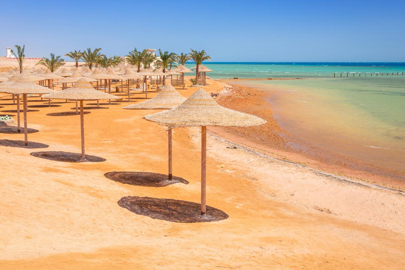 Gylden sandstrand med palmer og parasoller i Hurghada