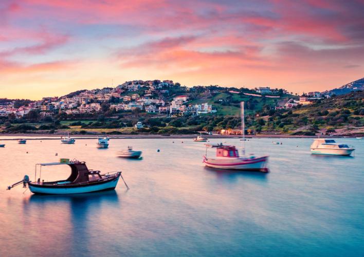 Kveldsstemning med småbåter på havet og Anavyssos by på Athens Riviera i Hellas