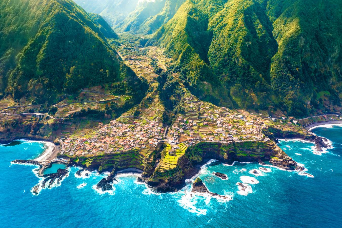 Dronebilde av fra Seixal, sett fra havsiden. Dette er en liten by på nordsiden av Madeira, som ender i klippeformasjoner mot havet og omgitt av frodig og grønnkledde åser i bakgrunnen.