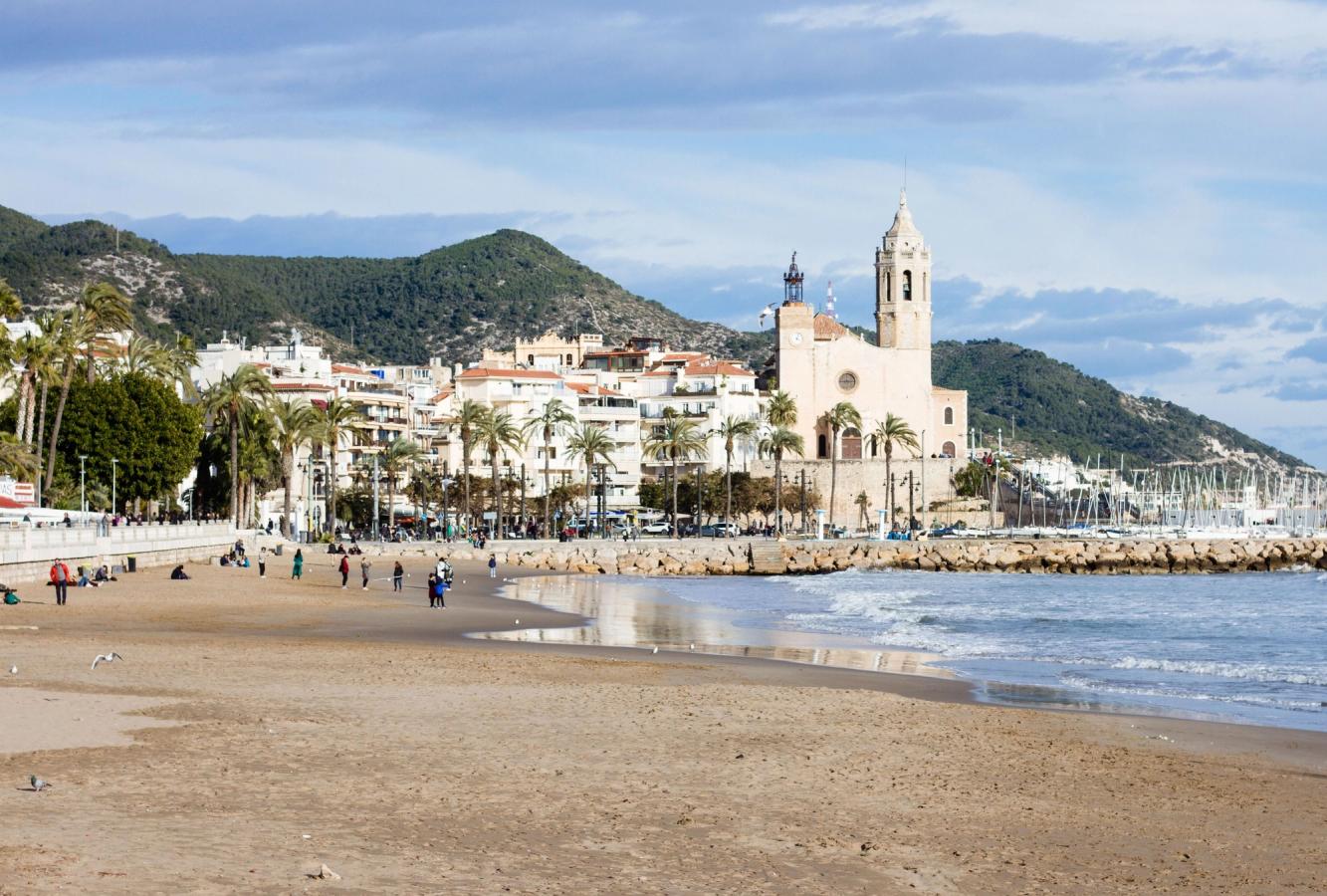 Utsikt over stranden og landemerket Sant Bartomeu kirken i Sitges