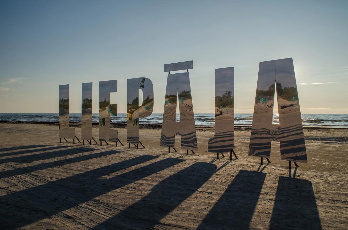 Bilden visar en stor skylt med ordet Liepaja på den breda sandstranden i Liepaja