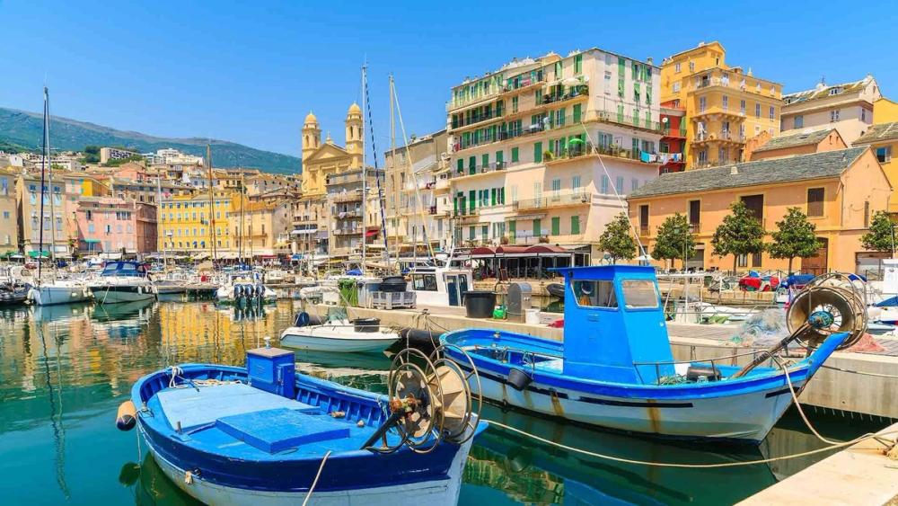 Havneområdet i Bastia på Korsika. Fremst i bildet med to mindre blå fiskeskøyter og med bebyggelse i bakgrunnen.