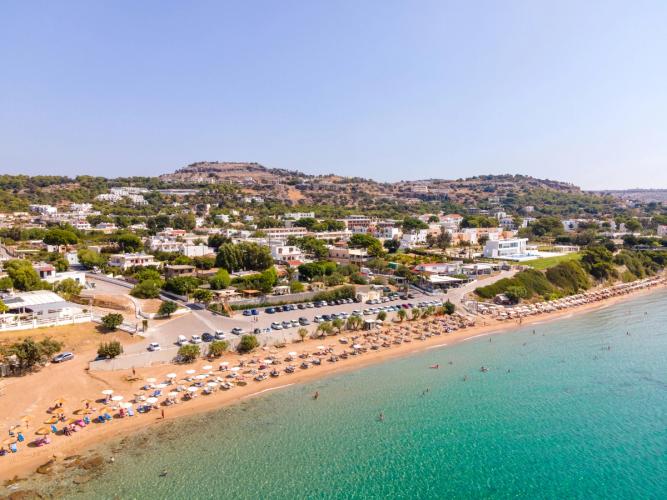 Bildet er fra stranda i Pefkos på Rhodos. Med den stille sjøen til høyre og den langstrakte stranda til venstre. Alt under en skyfri himmel.