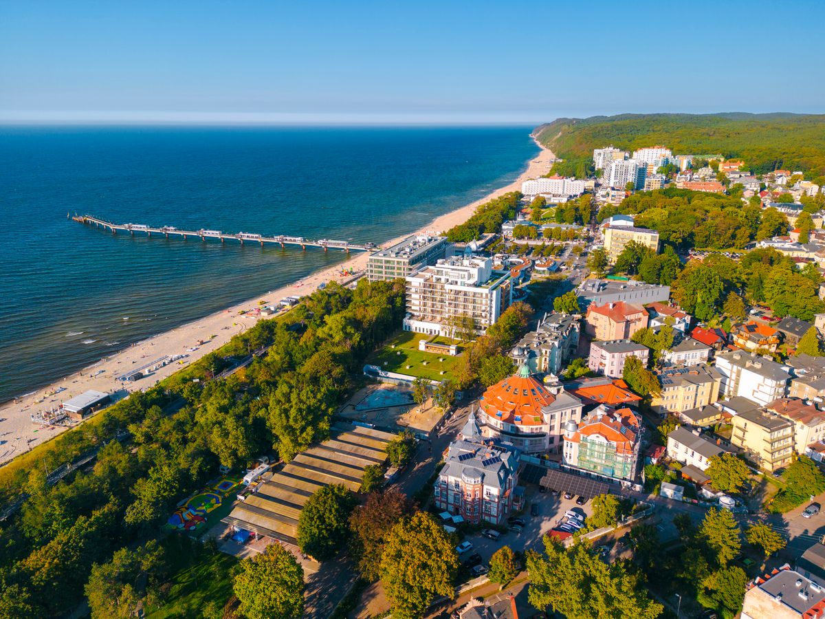 Bilden visar den långa stranden längs Östersjön vid staden Miedzyzdroje. Havet och stranden till vänster i bilden övergår till grön vegetation och mindre bebyggelse till höger.