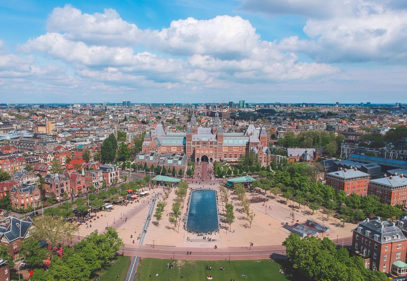 Dronebillede af Rijksmuseum i Amsterdam med parken og vandspejlet i forgrunden.