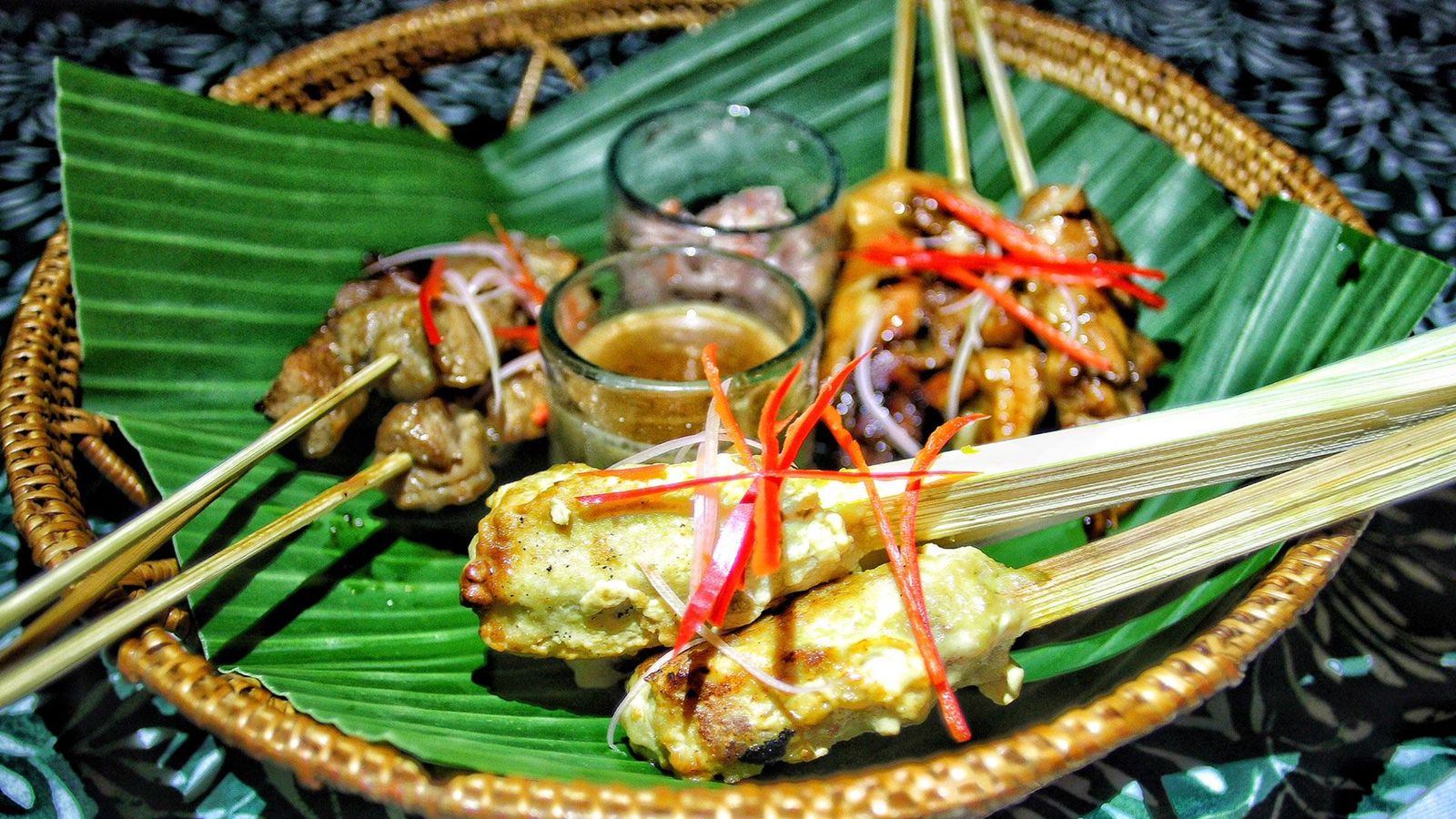 Forskjellige typer grillspyd ligger i en liten kurv på et stykke grønt papir.