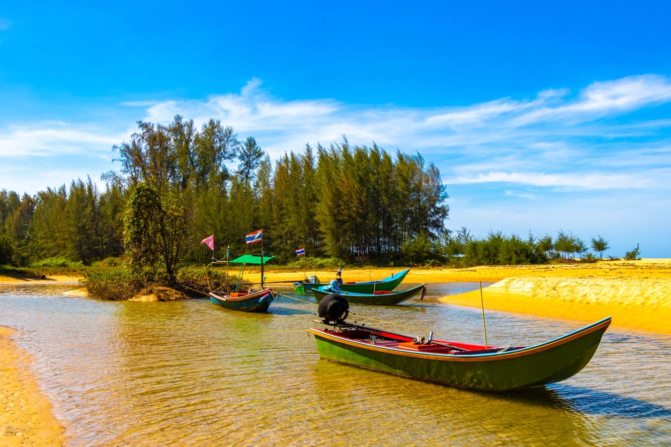 Typiske båter på elven med gyllengule strender i det tropiske paradiset Khao Lak i Thailand