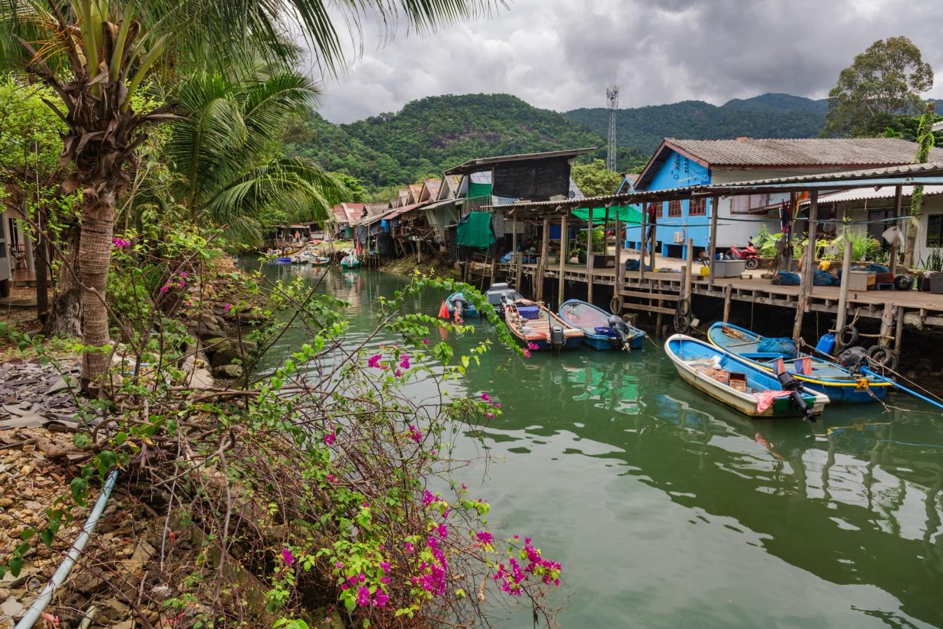 Traditionella båtar på floden som rinner ut vid Kai Bae beach på Koh Chang i Thailand