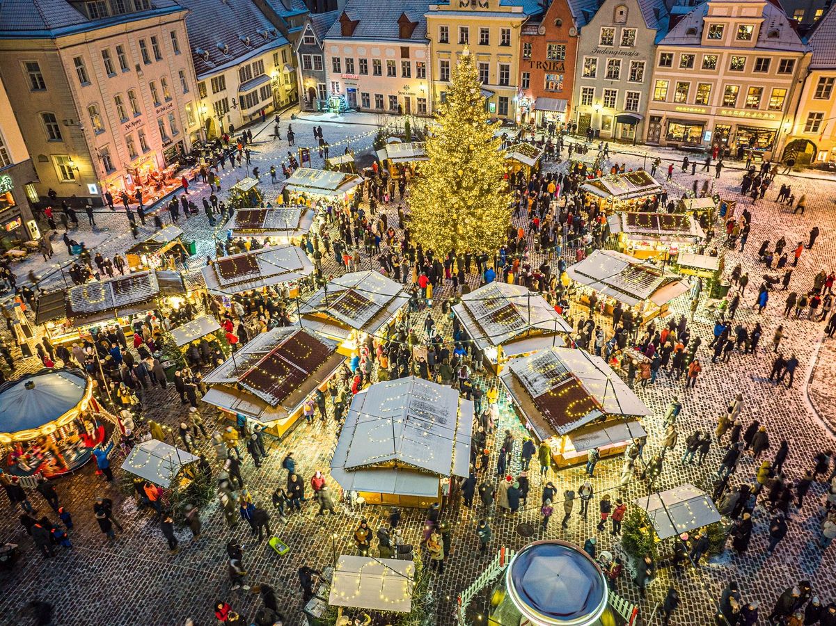 Bildet viser et hyggelig julemarked i Tallinn. Her er det massevis av julelys, boder, mennesker og et stort juletre i midten. 