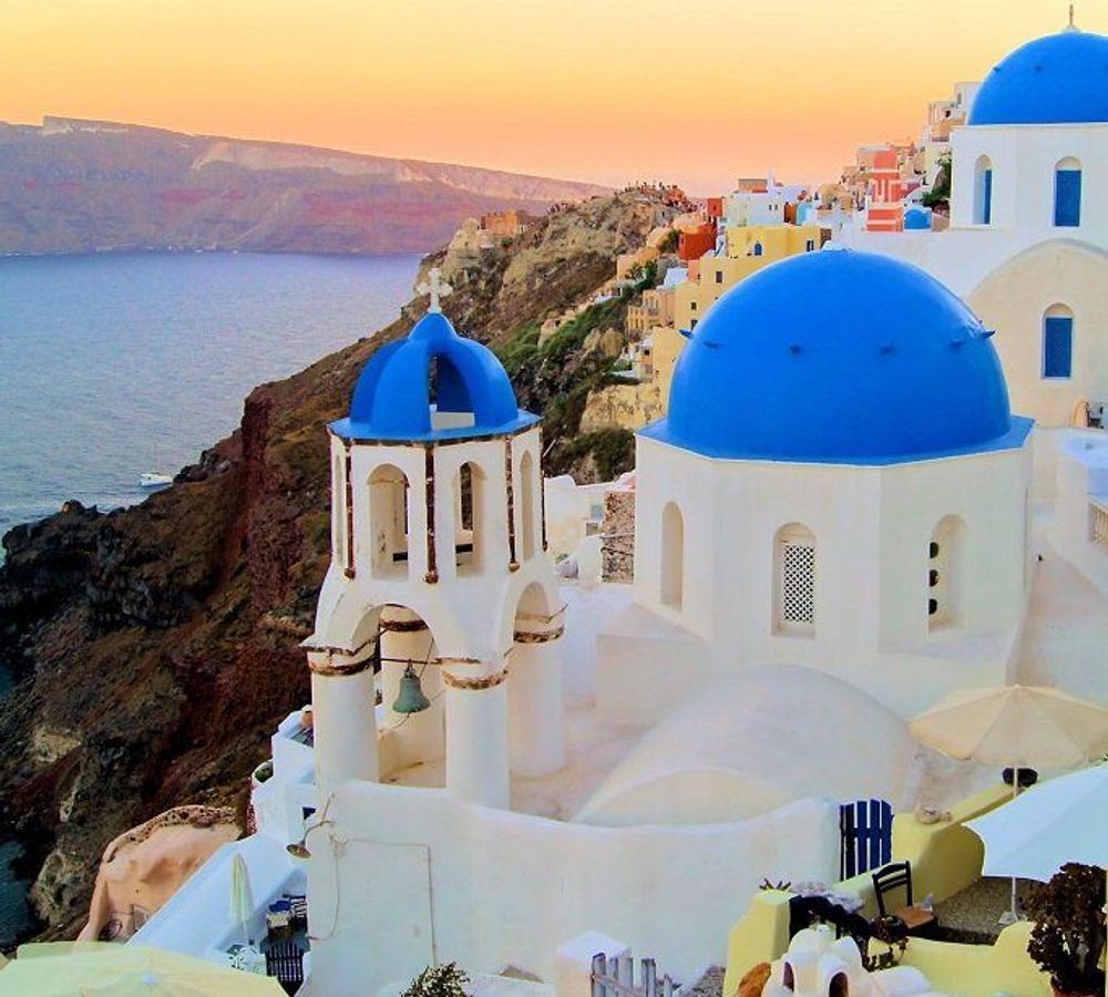 Bildet viser solnedgangen over Santorini med hvitkalkede hus og blå kupler