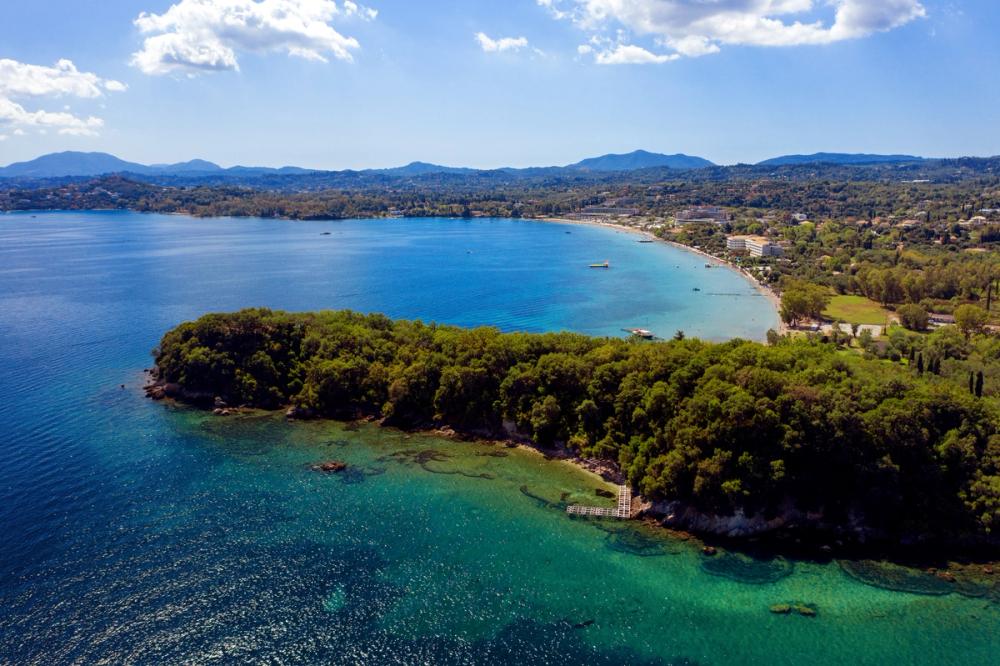 Panoramautsikt over Dassia omkranset av den frodige naturen og krystallklart hav på Korfu i Hellas