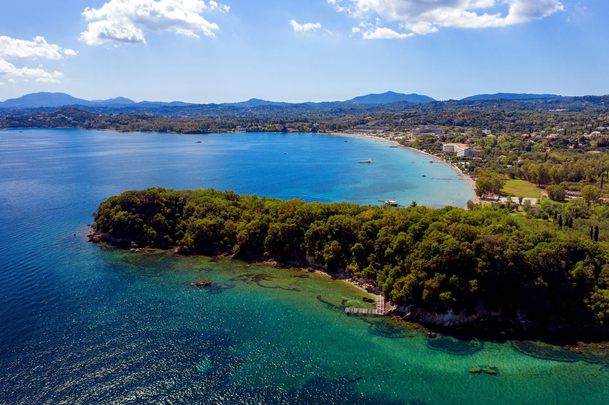 Panoramautsikt over Dassia omkranset av den frodige naturen og krystallklart hav på Korfu i Hellas