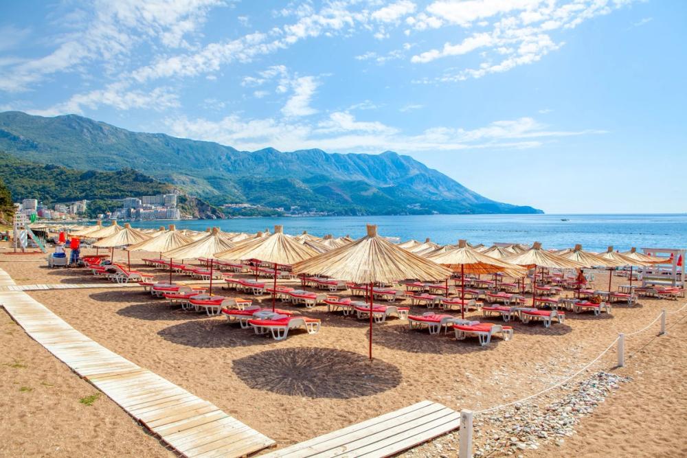 Utsikt over stranden med solstoler og parasoller i Becici i Montenegro
