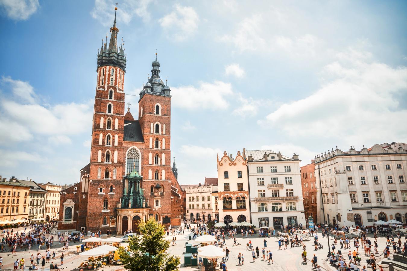 Billedet viser den gamle bydel i Krakow med St. Mary's Basilica centralt i billedet. Mariakirken består af to høje tårne med spir. Omkring kirken ses ældre bebyggelse og en åben torveplads.
