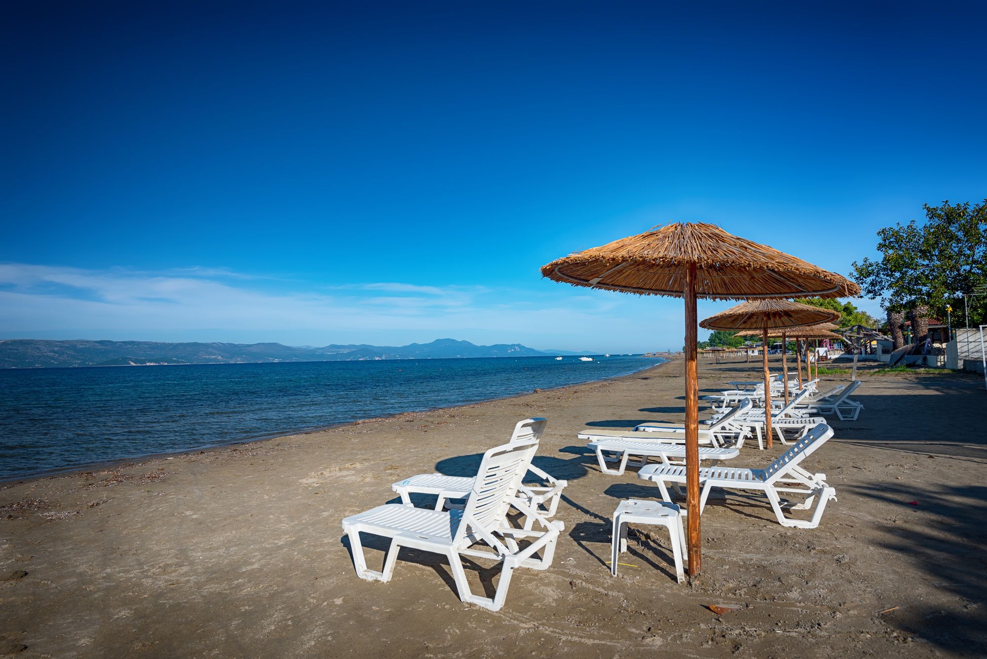 Utsikt over stranden med solstoler og det blå havet i Kavos på sørsiden av øya Korfu i Hellas
