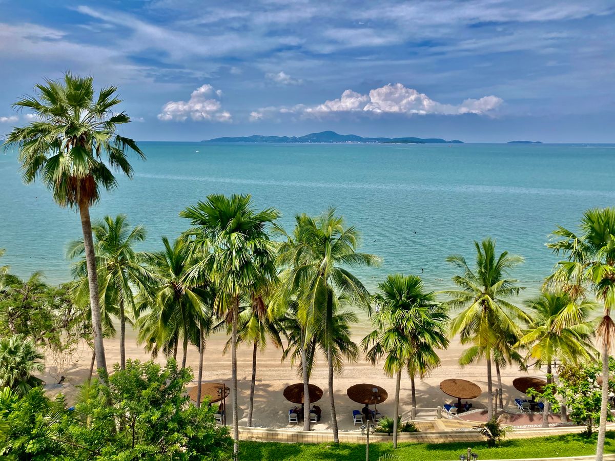 Stranden i Hua Hin med palmer og solstole og med udsigt over Thailandbugten
