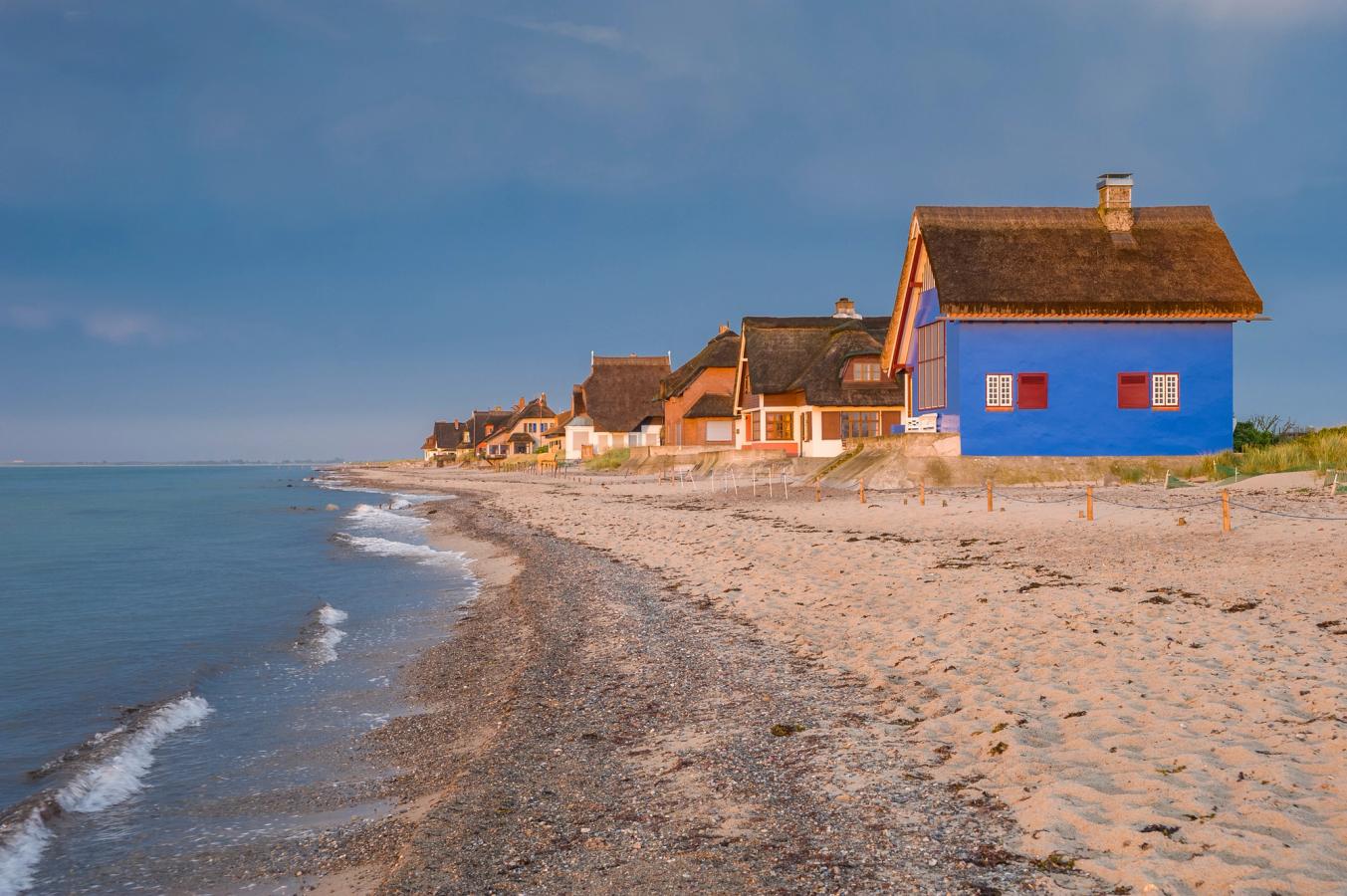 Billedet viser den dejlige sandstrand ved Heiligenhafen med stråtagshuse lige ved strandkanten