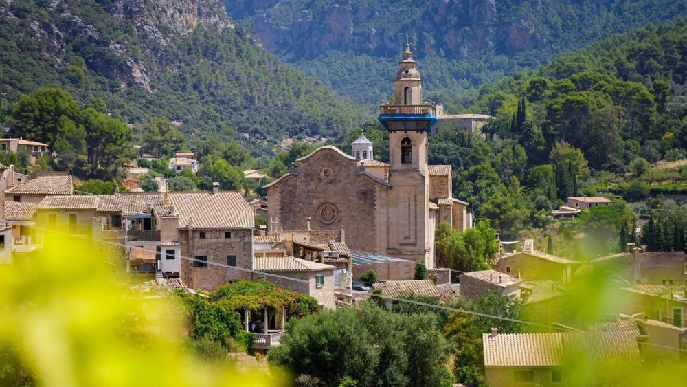 Kirketårnet i Valldemossa rejser sig over byens stenhuse. Byen er omkranset af Tramuntanabjergene