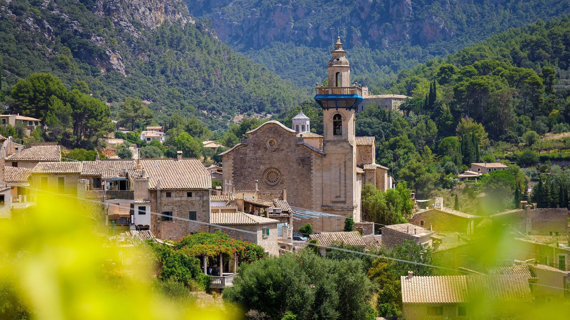 Kirketårnet i Valldemossa rejser sig over byens stenhuse. Byen er omkranset af Tramuntana-bjergene