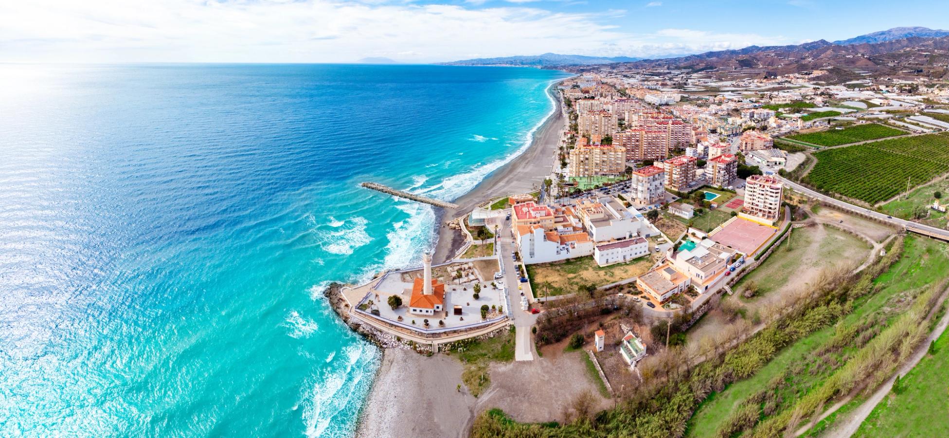 Flygfoto över Torrox Costa på Costa del Sol med det karaktäristiska fyrtornet vid kusten, breda stränder och det turkosblå Medelhavet längs staden