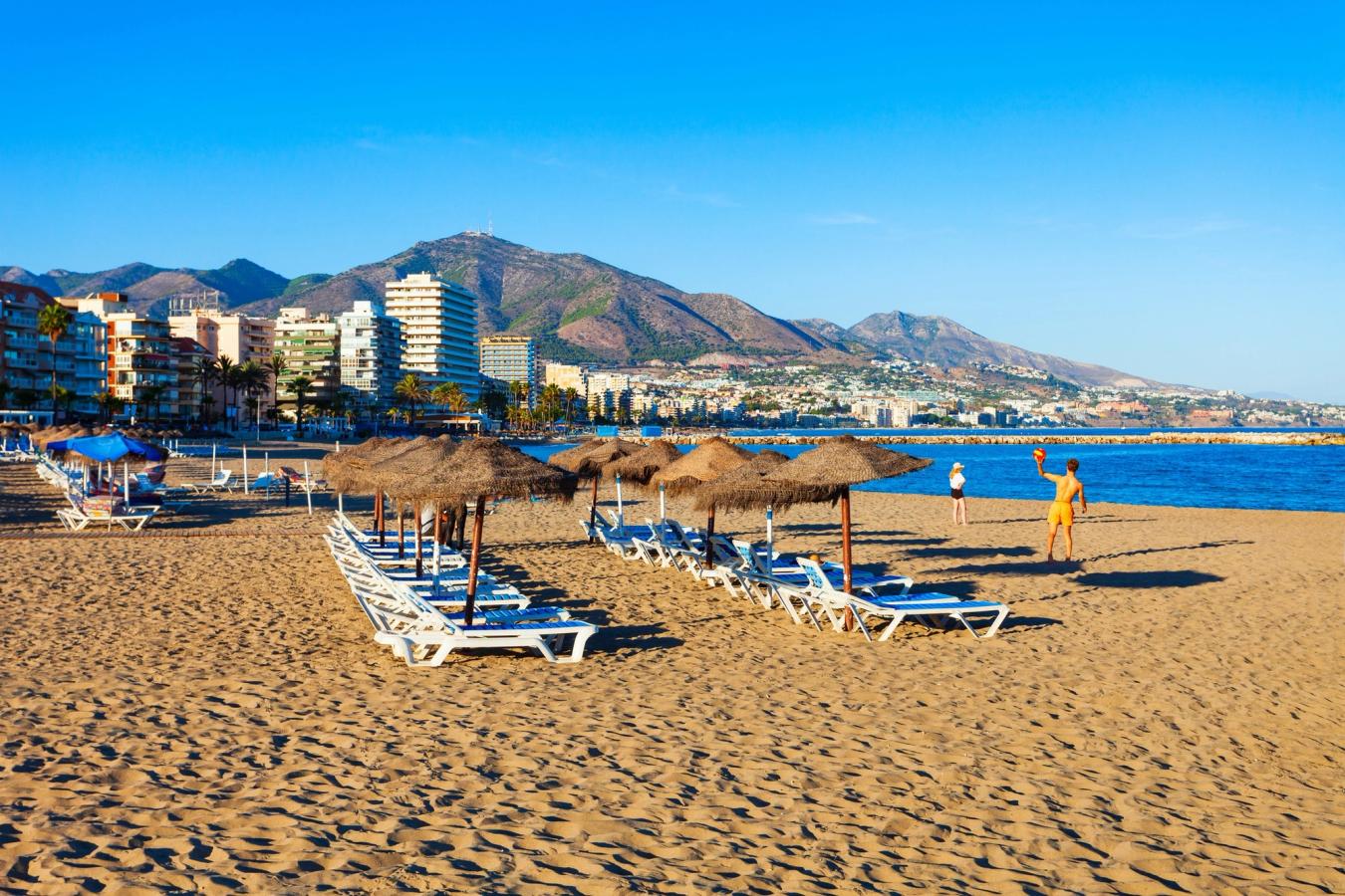 Udsigt over strandlinjen ved Fuengirola med solsenge, parasoller og byens bebyggelse i baggrunden