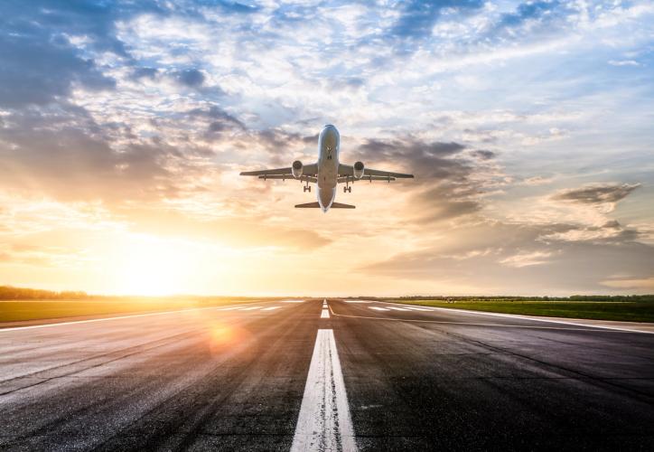 Fly som tar av fra rullebanen med sola i bakgrunnen