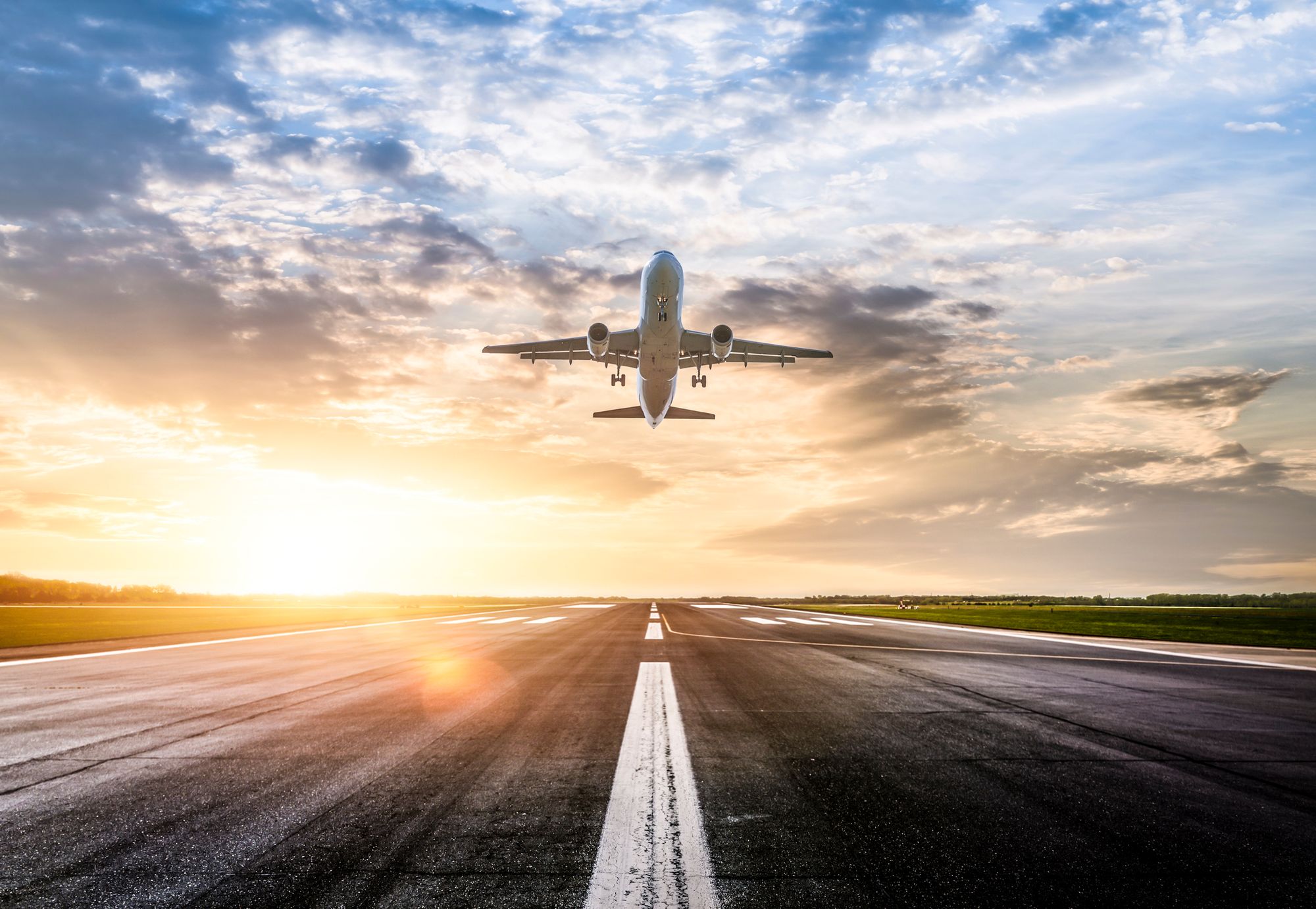 Fly som tar av fra rullebanen med sola i bakgrunnen
