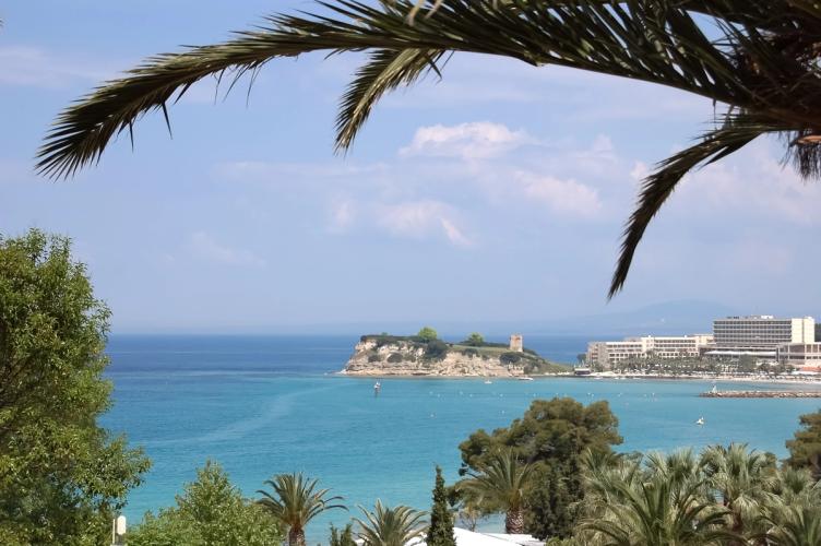 Utsikt over det krystallklare havet med palmer, strand og hoteller i Sani i Halkidiki, Hellas