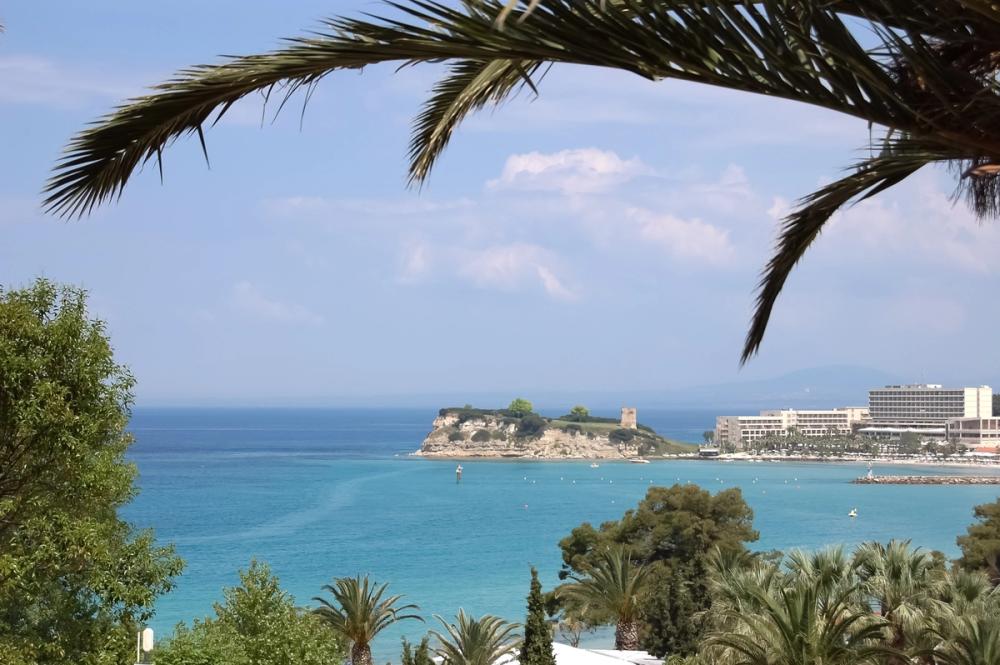 Utsikt over det krystallklare havet med palmer, strand og hoteller i Sani i Halkidiki, Hellas