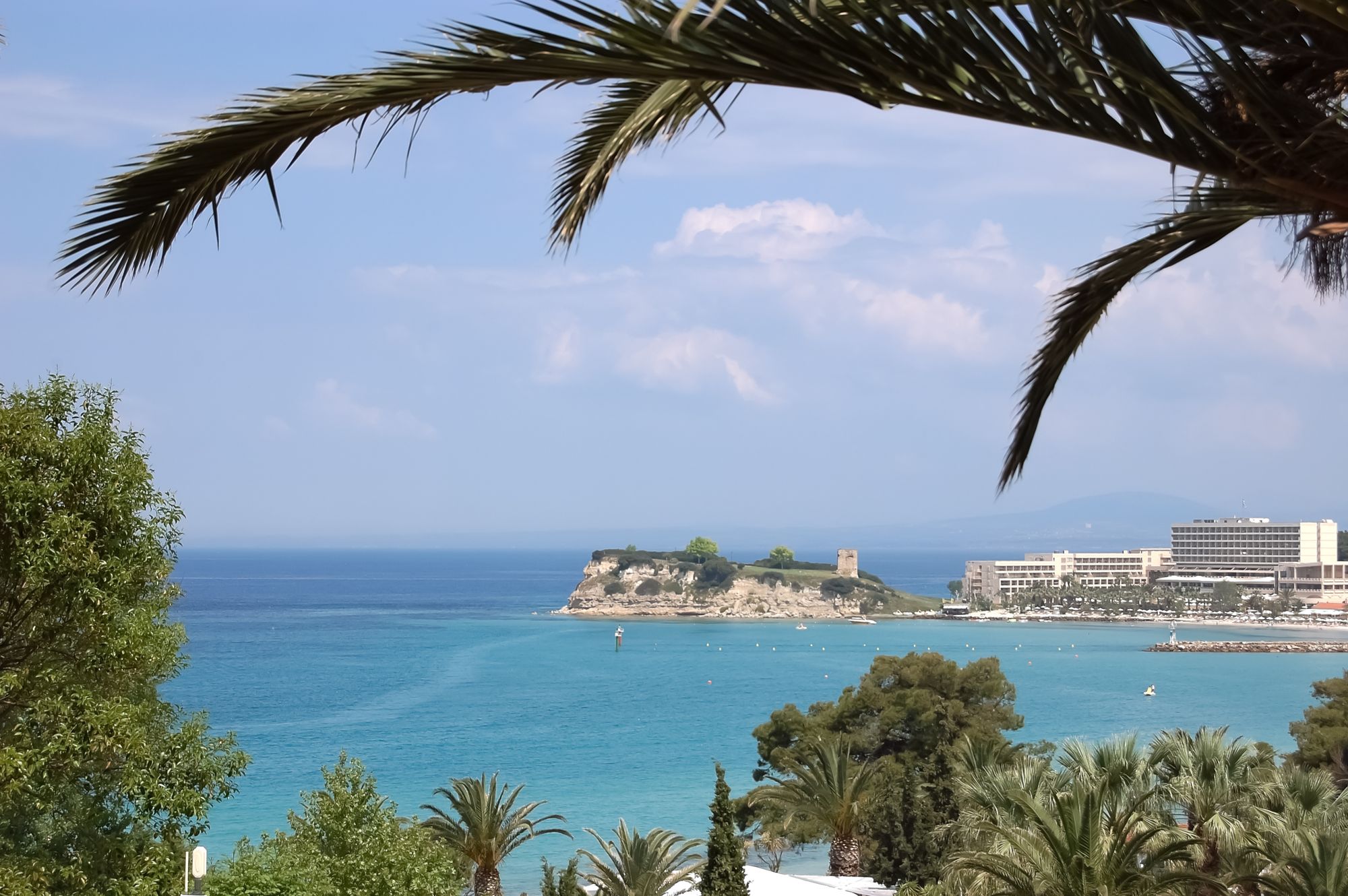 Utsikt over det krystallklare havet med palmer, strand og hoteller i Sani i Halkidiki, Hellas