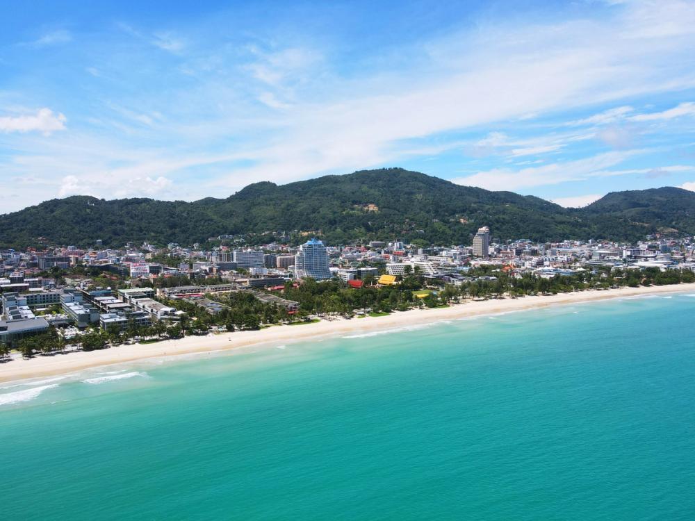 Utsikt over Patong Beach i Phuket og den hvite sandstranden med grønnkledde åser i bakgrunnen, Thailand