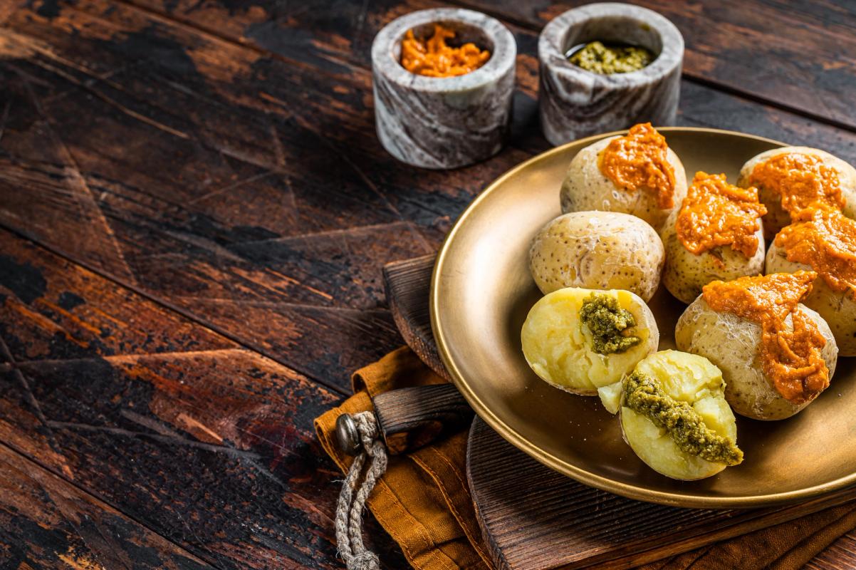 Billede af papas arrugadas, typiske kanariske kartofler med rød mojo-sauce. Anrettet på et brunt træbord.