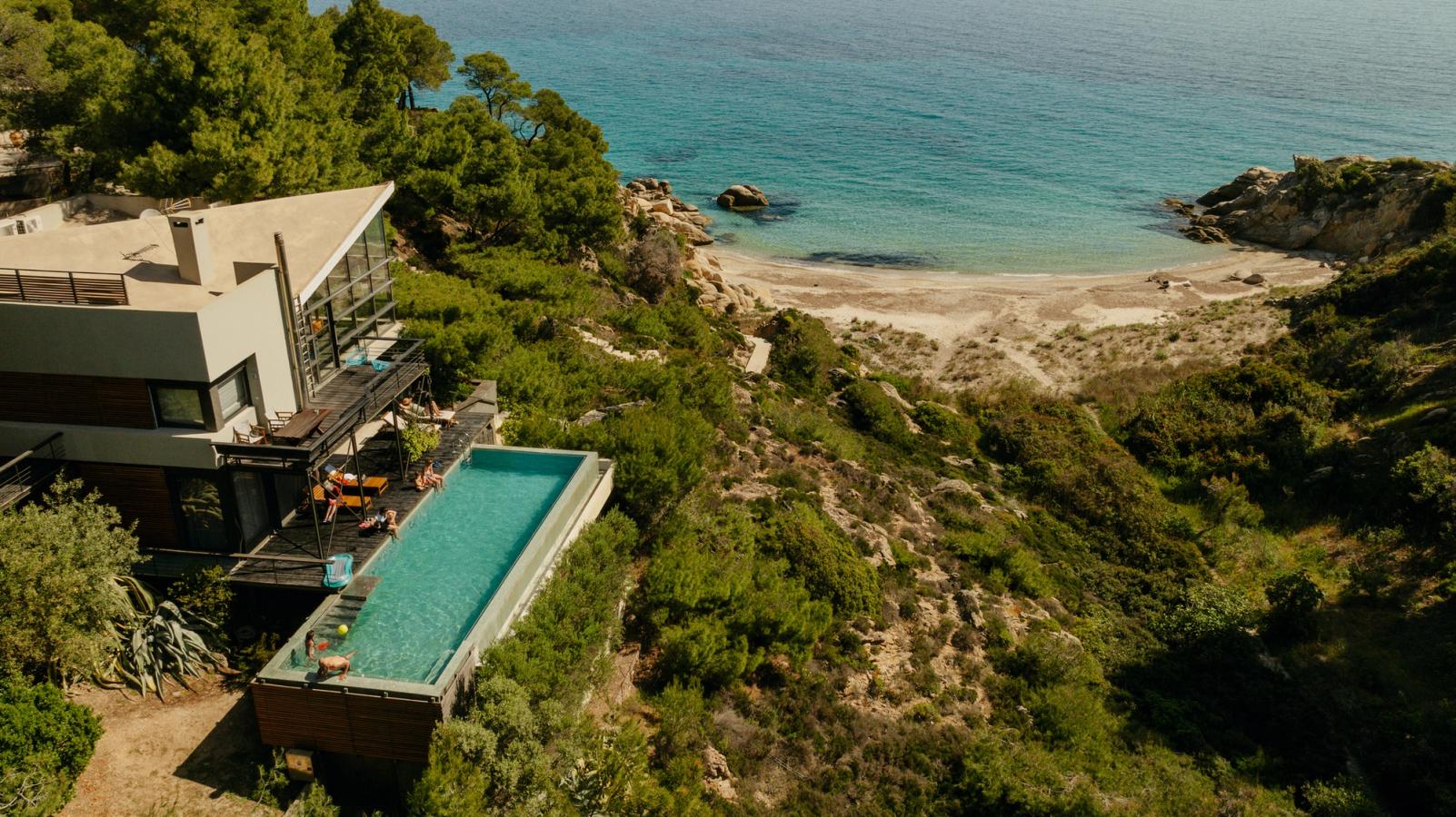 Flere generationer i en familie bor i et feriehus med pool og en strand lige nedenfor