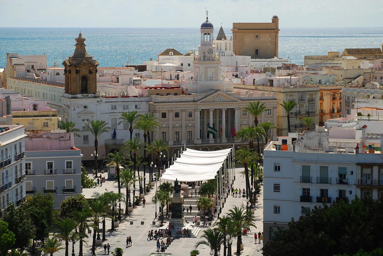 Udsigt over Cadiz’ historiske centrum med rådhuset, palmer og havet i baggrunden.