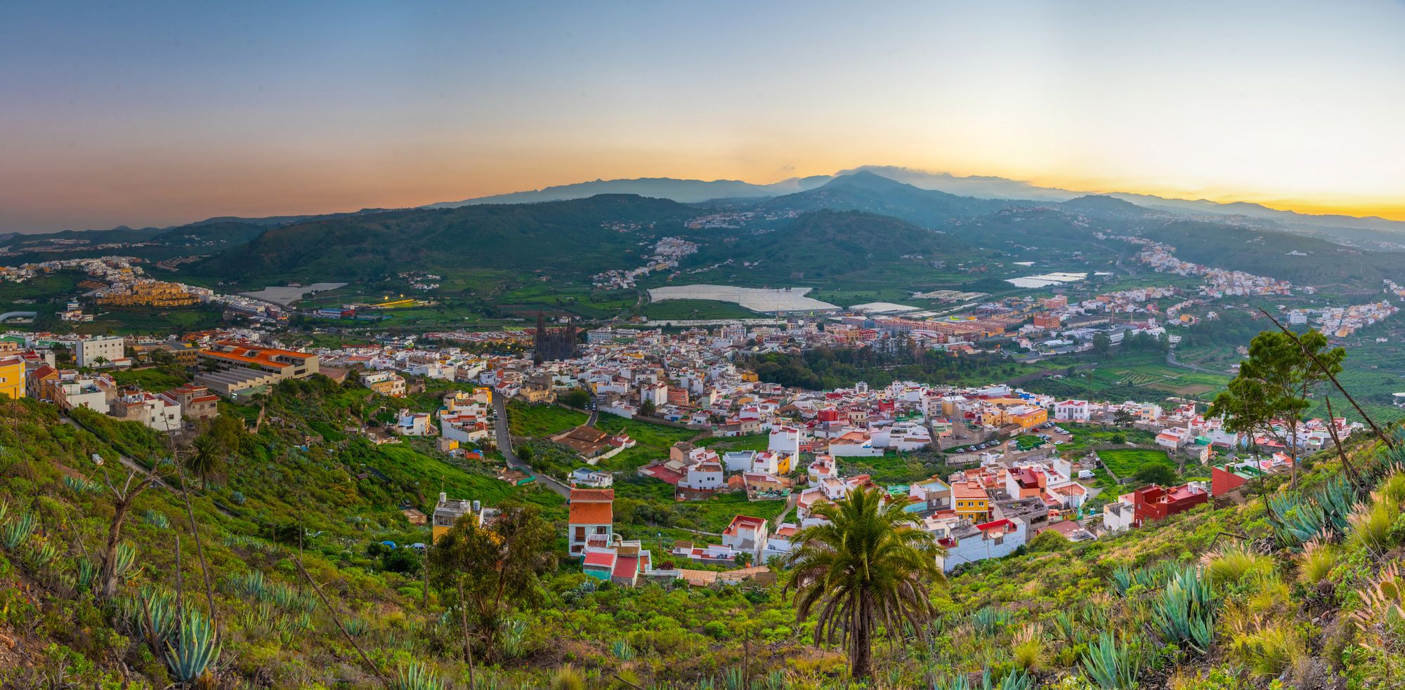 Udsigt over Arucas på Gran Canaria omkranset af smuk, grøn natur i solnedgang