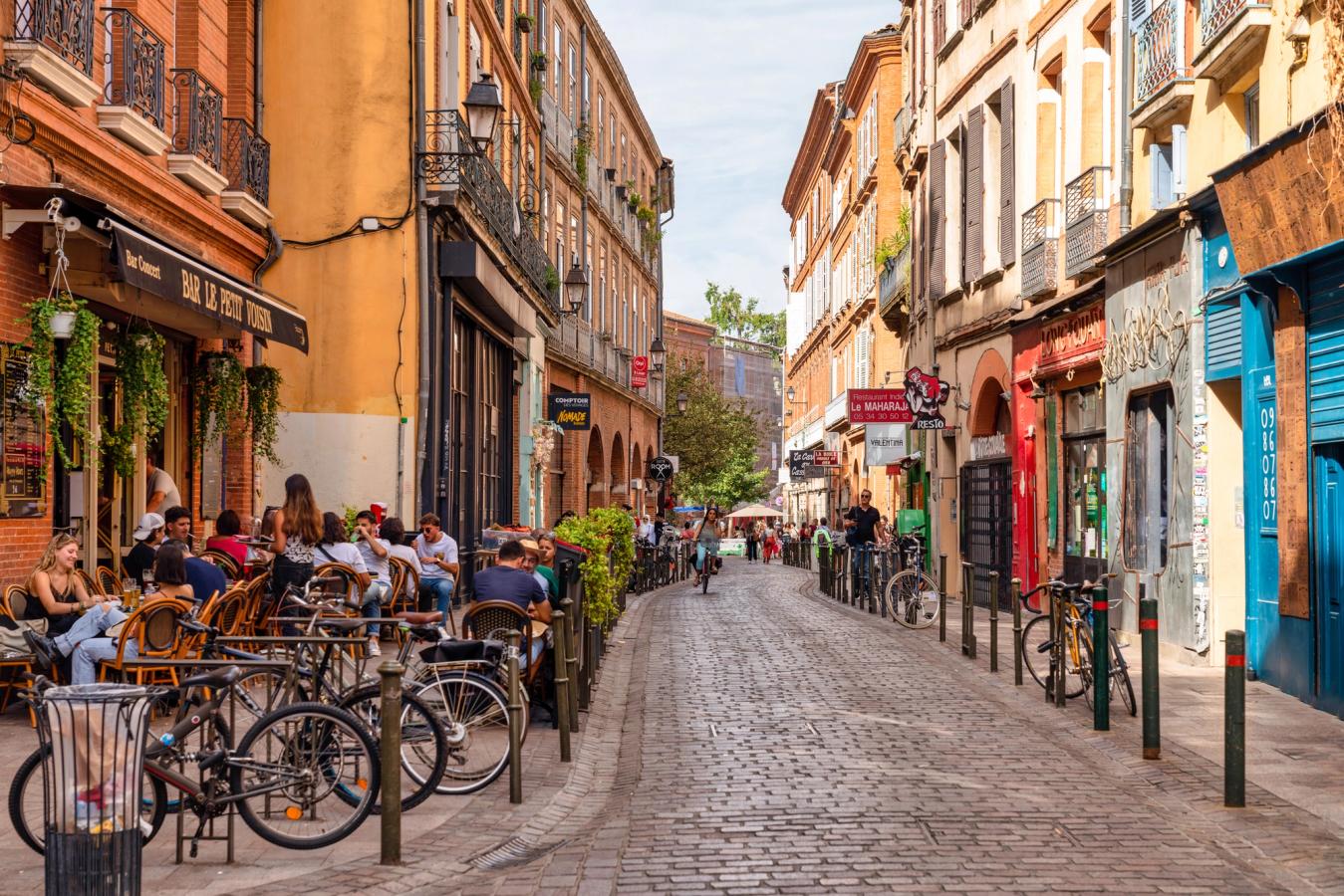 Hyggelige gater med fortauskafeer og fargerike hus i Toulouse i Frankrike