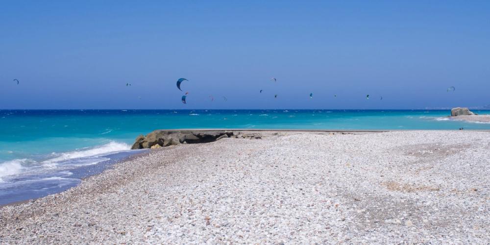Bildet viser Kremasti Beach med en rekke kitere ute på sjøen. Vannet har den vakre smaragdgrønne fargen og alt under en skyfri himmel