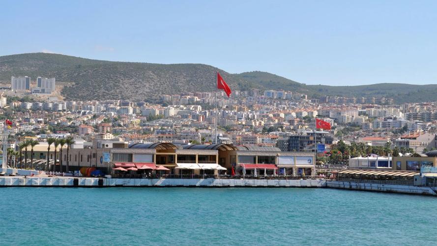 Kusadasi sett fra sjøsiden med uteserveringer og fjellene i horisonten, Tyrkia