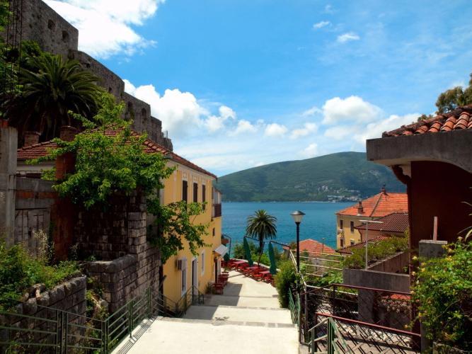 Utsikt over sjøen og husene langs en smal gate i Herceg Novi i Montenegro