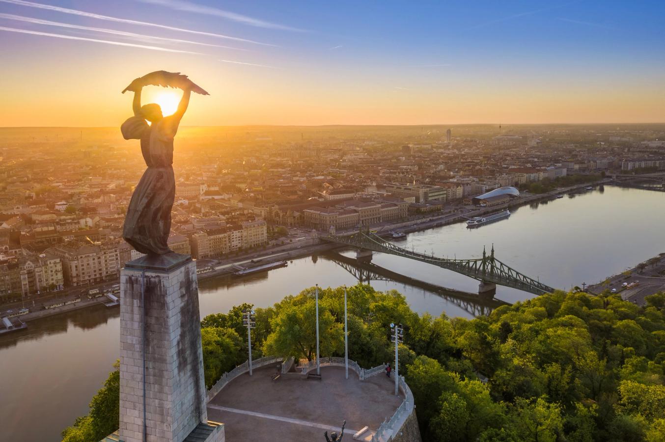 Frihetsgudinnen med utsikt over byen og Frihetsbroen i Budapest i soloppgang