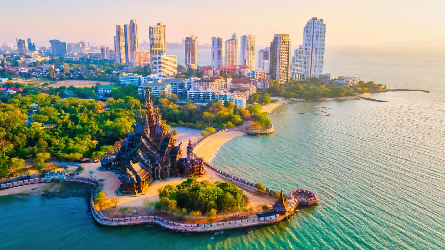 Bildet viser Pattaya by med skyskrapere i midten og inn i bildet. Nærmest i bildet ser vi et tempel helt mot vannkanten.