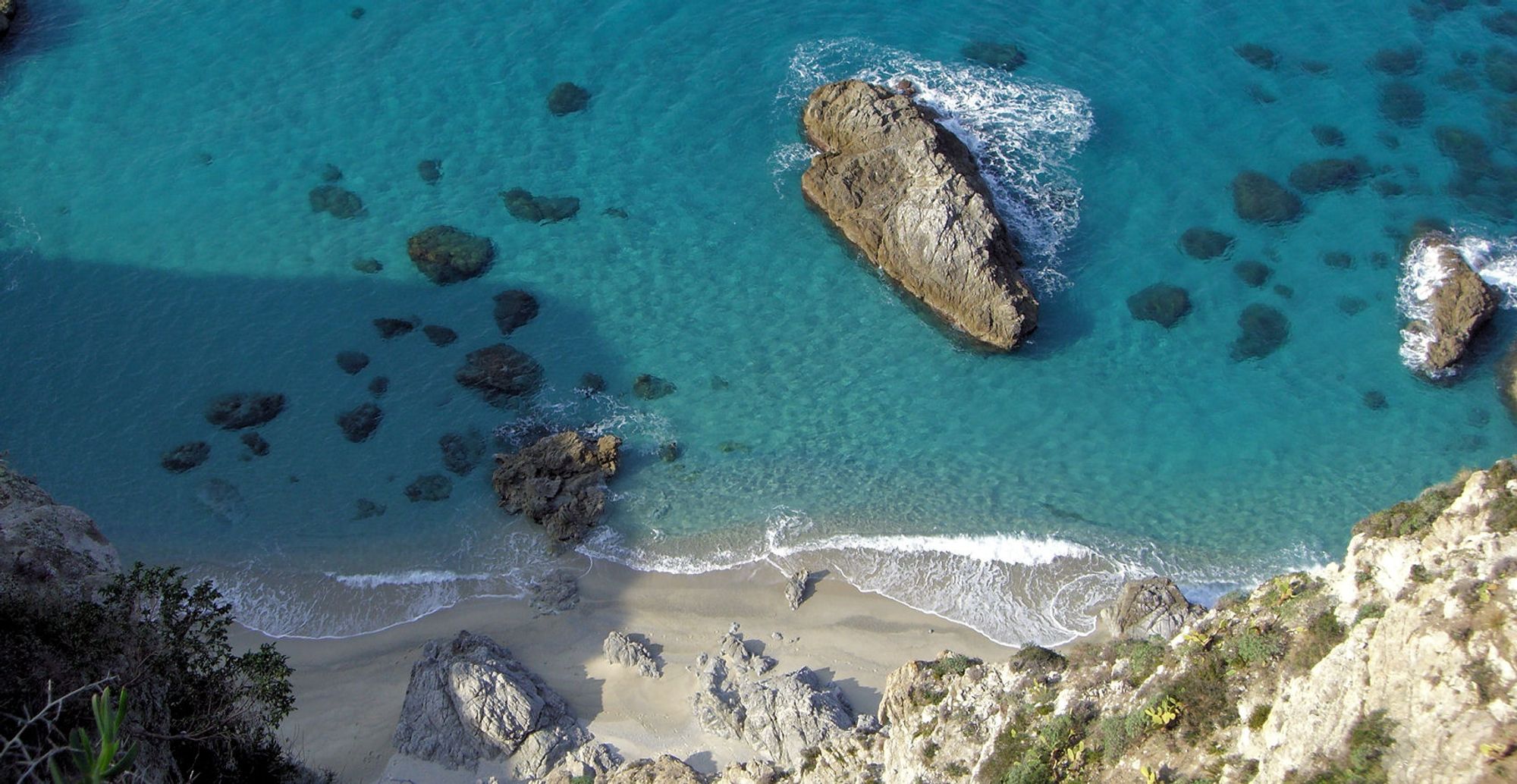 Klipper og hvit sandstrand langs kysten i Calabria i Italia