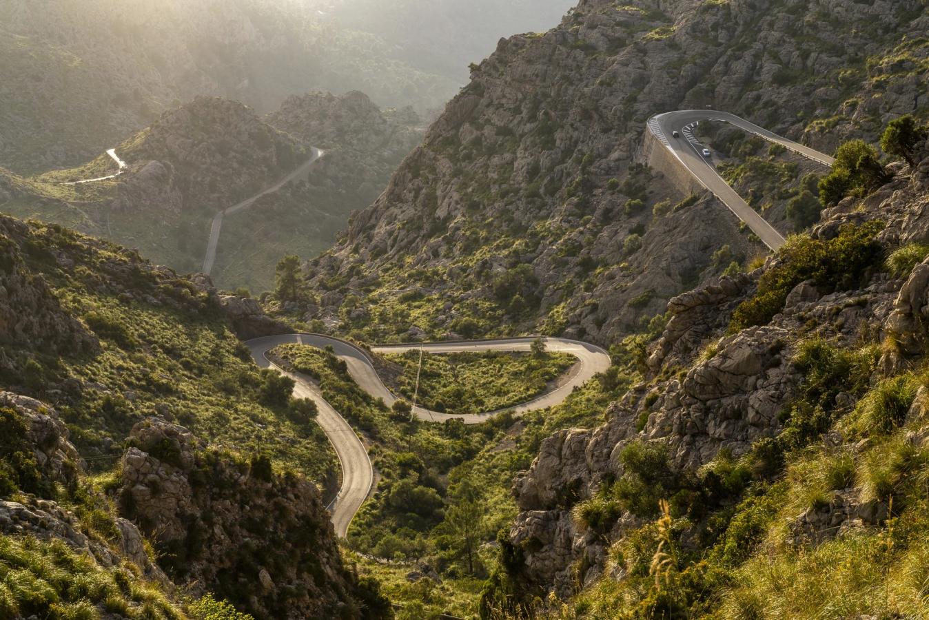 Billede af hårnålesving i bjergkæden Tramuntana på Mallorca. Stejle og frodige bjergskråninger på hver side af vejen.