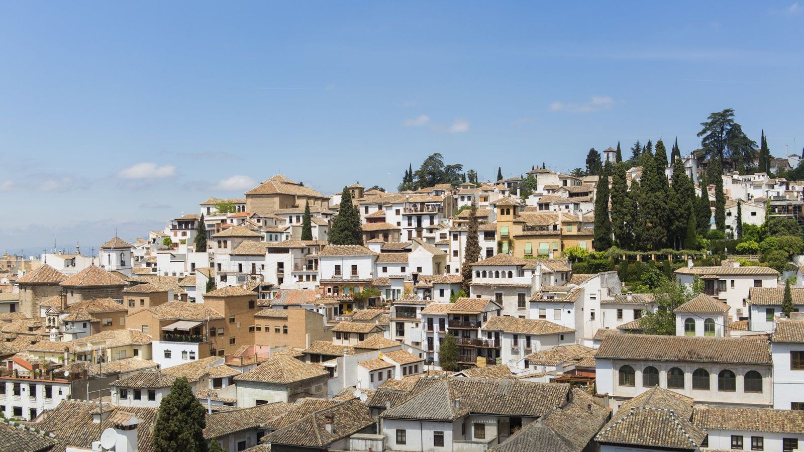 Hvidkalkede huse og smalle gader, der skråner opad på en høj i bydelen Albaicín i Granada
